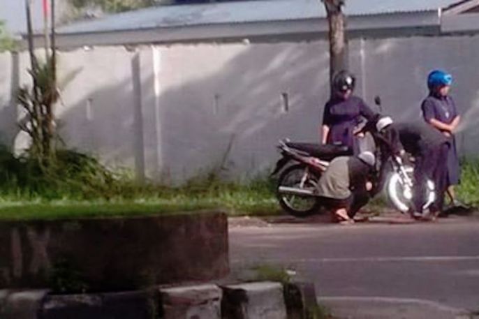 Foto pria muslim memperbaiki motor biarawati yang mogok 